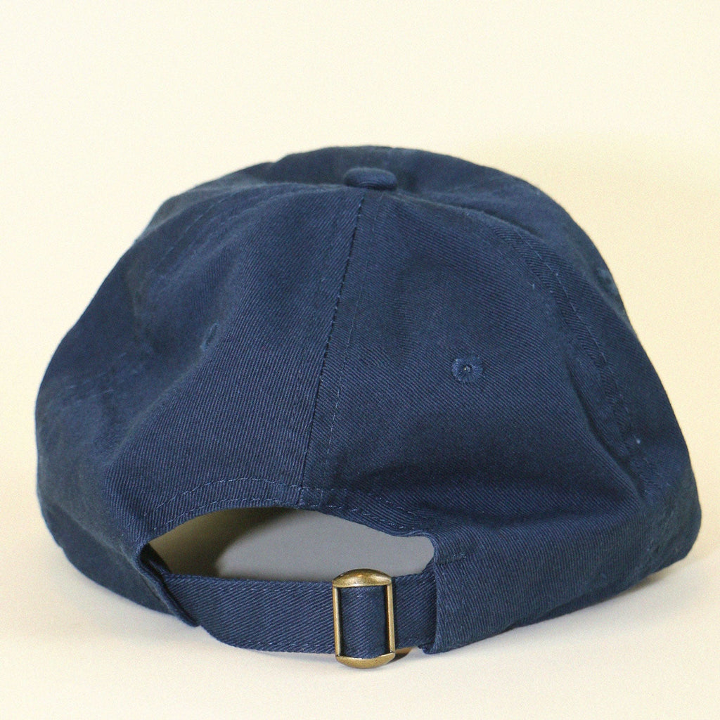 Back of navy blue baseball cap with adjustment buckle on beige backdrop