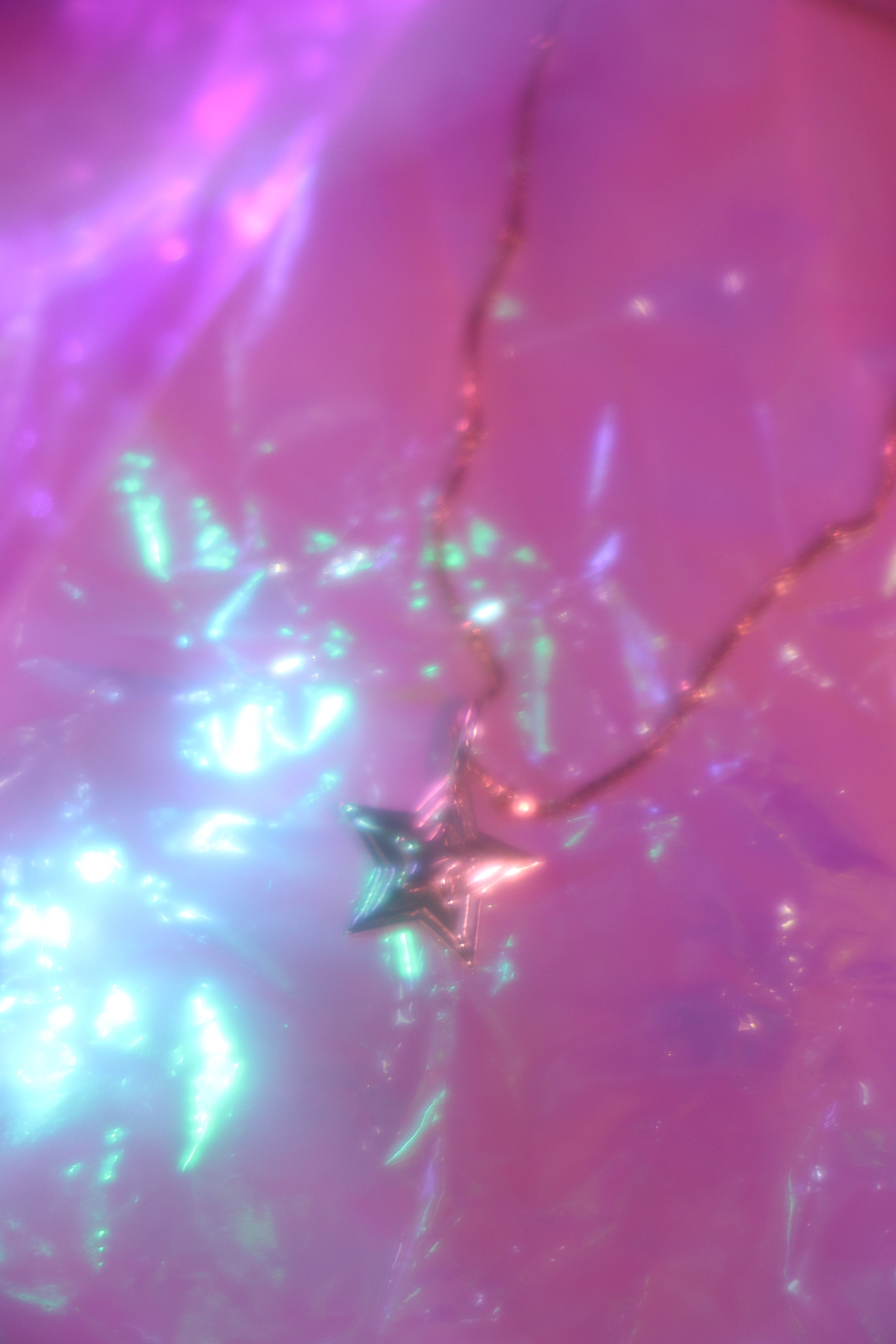 brass 3-d layered starburst charm hanging from brass chain on a dreamy background