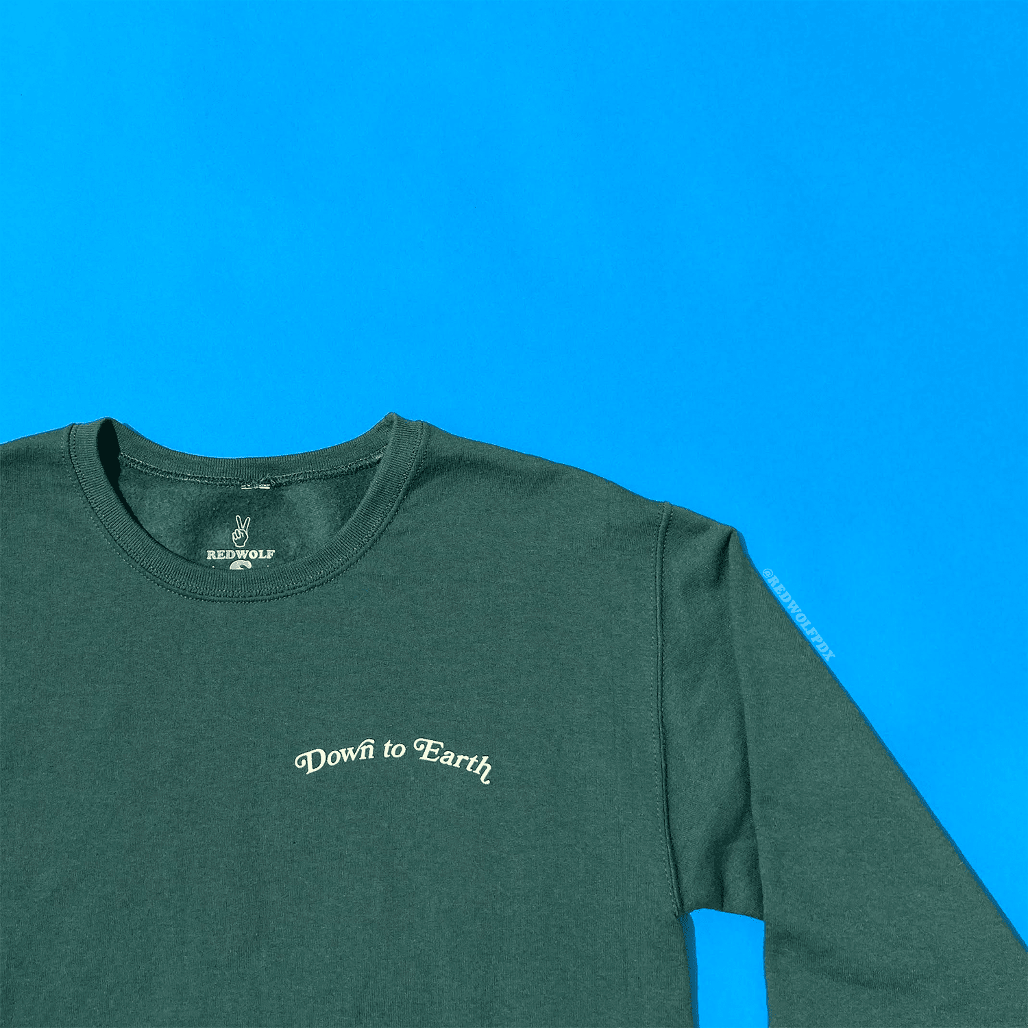 'DOWN TO EARTH' text graphic crewneck on blue backdrop 