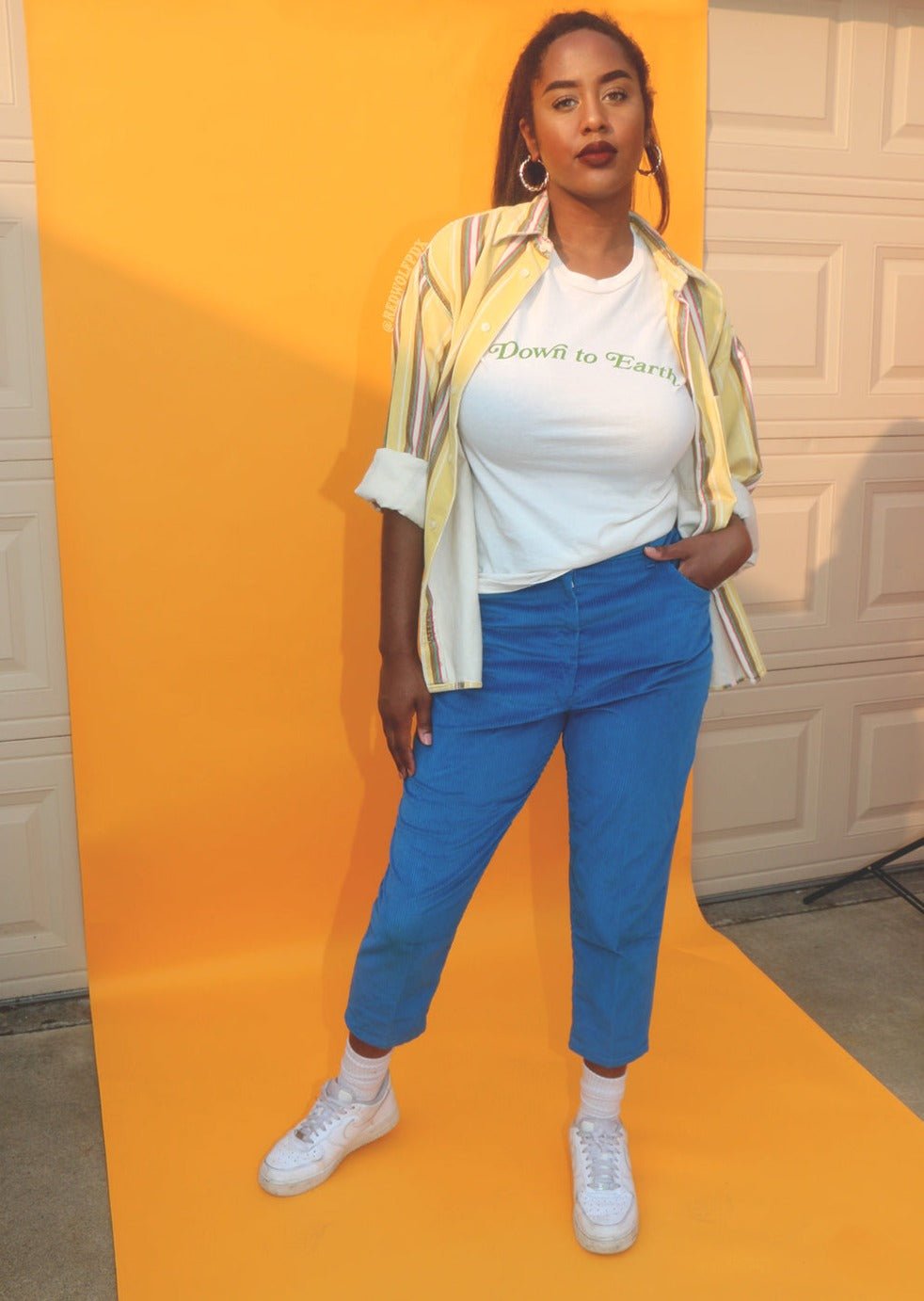 Down to earth graphic tee being worn in front of a yellow backdrop 