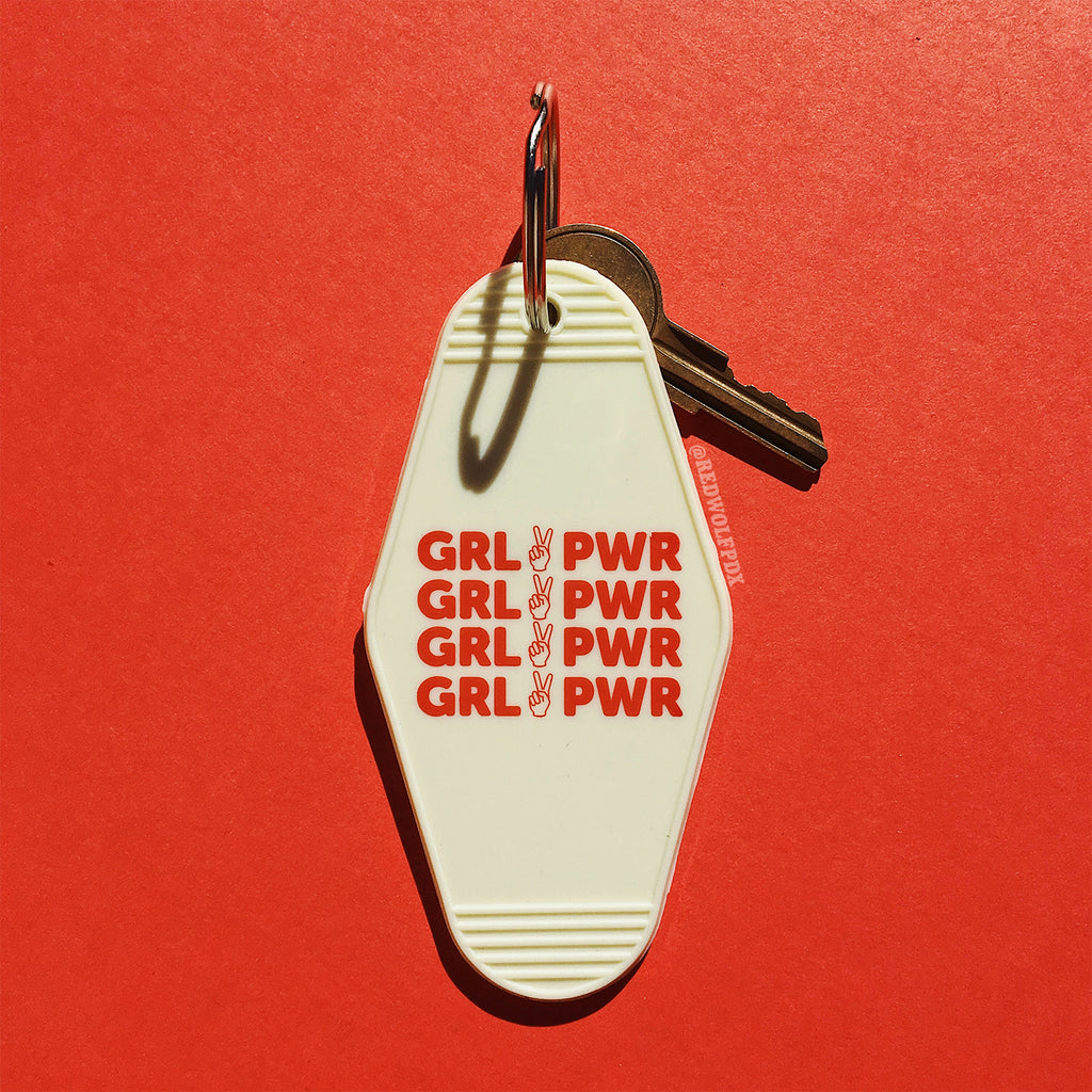 A vintage white keychain with the text 'GRL PWR' in red on a red background