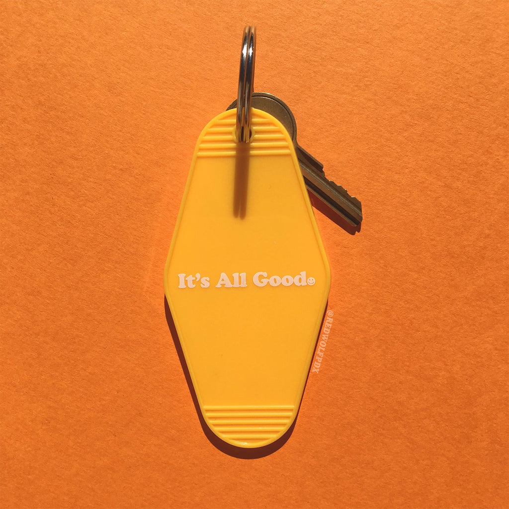 yellow motel style keychain with text 'It's All Good' with smiley face graphic on an orange background
