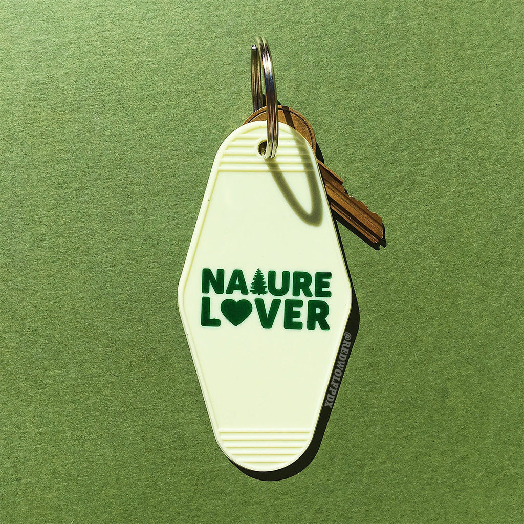 A vintage white keychain with the text 'NATURE LOVER' in dark green, shaped like a motel key on a green background
