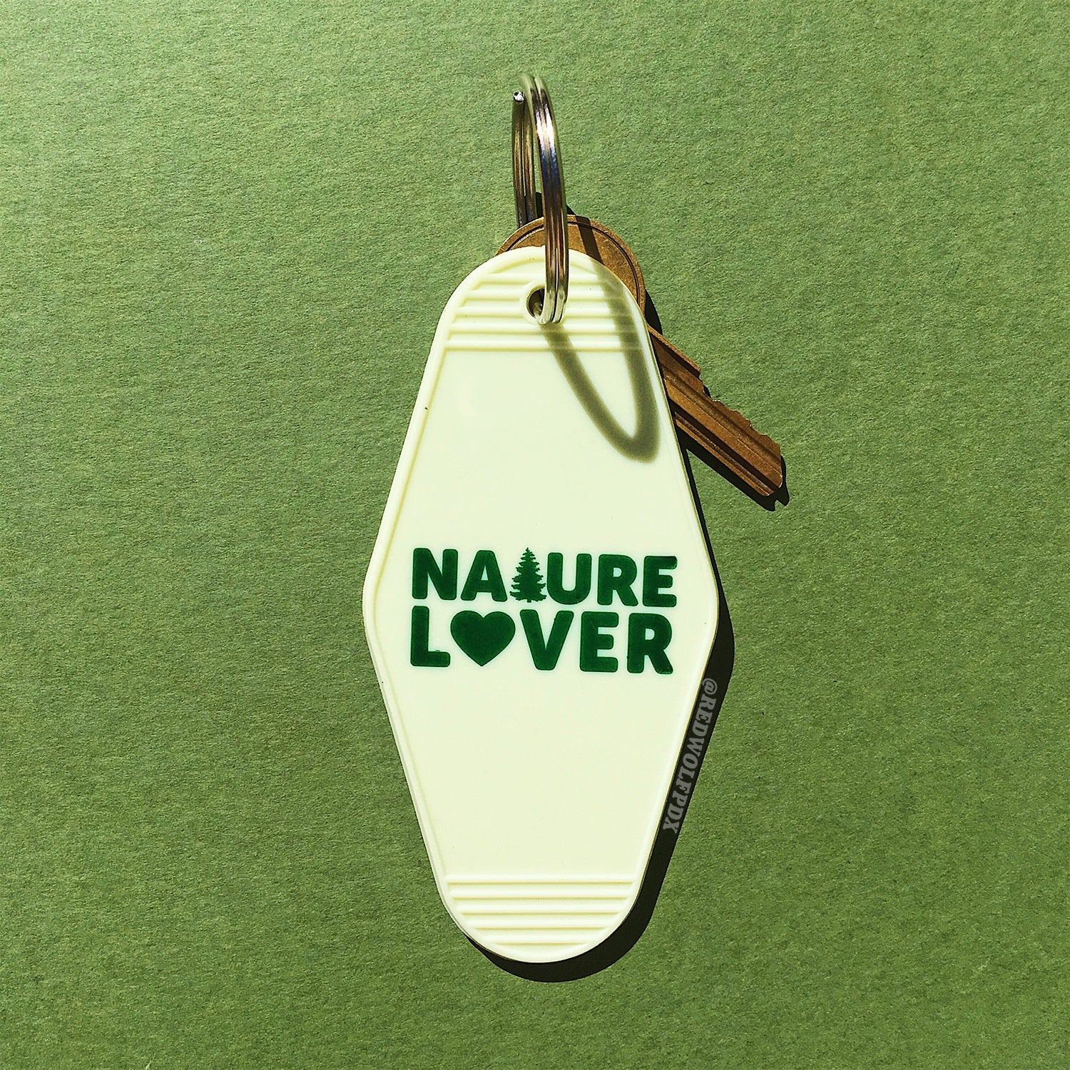 A vintage white keychain with the text 'NATURE LOVER' in dark green, shaped like a motel key on a green background