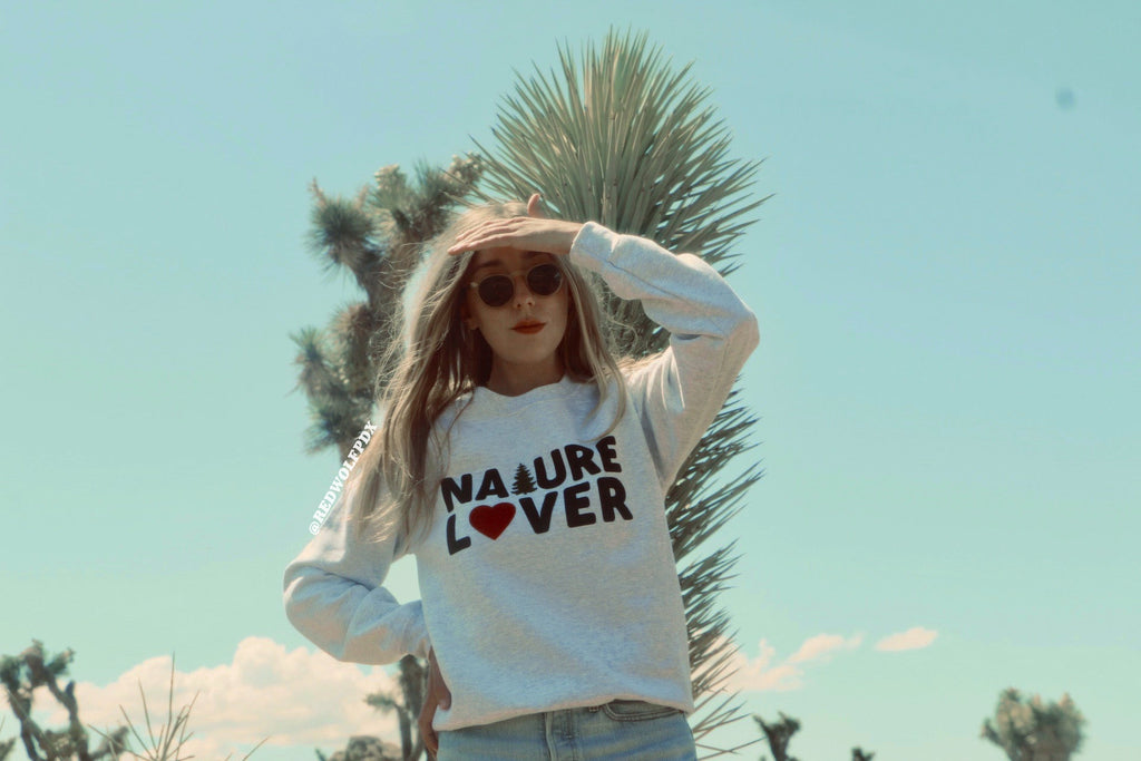 heather grey crewneck with text 'NATURE LOVER' across the chest being worn in a nature backdrop