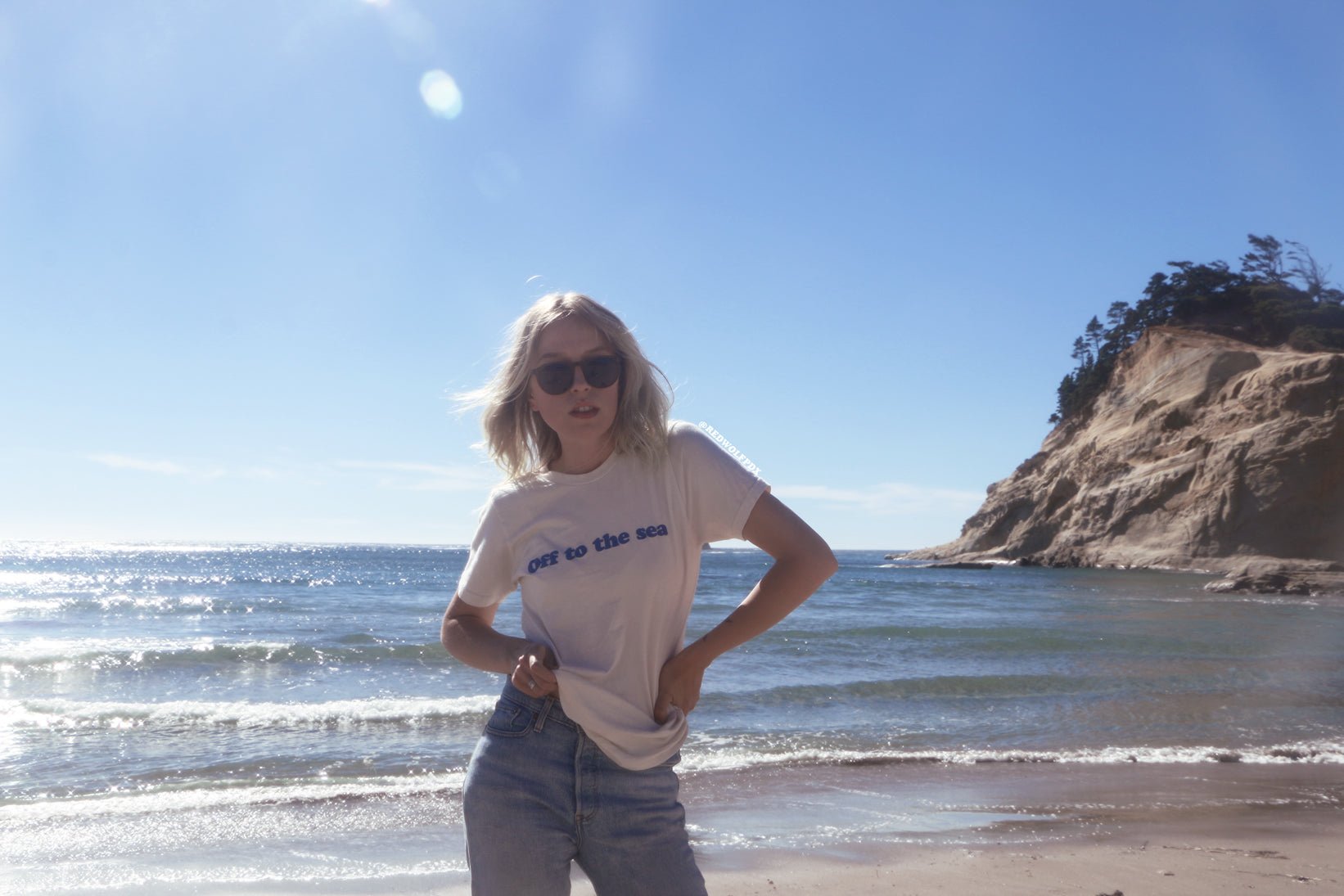 off to the sea tee being worn at beach in background