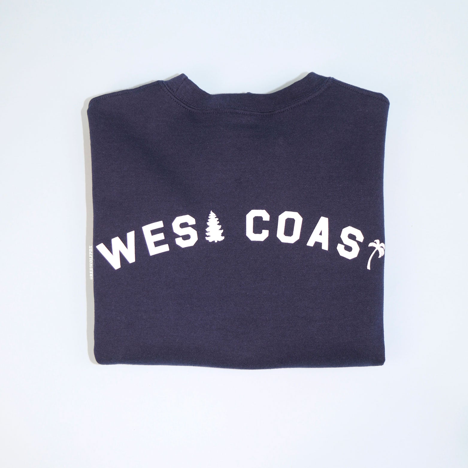 Navy blue sweatshirt with the text 'WEST COAST' printed in white across the back