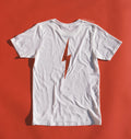 White graphic tee with lightening bolt in vintage red ink screen printed down the back of tee against a vintage red backdrop